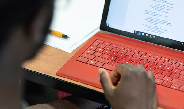 A student uses a mouse pad in a red laptop computer